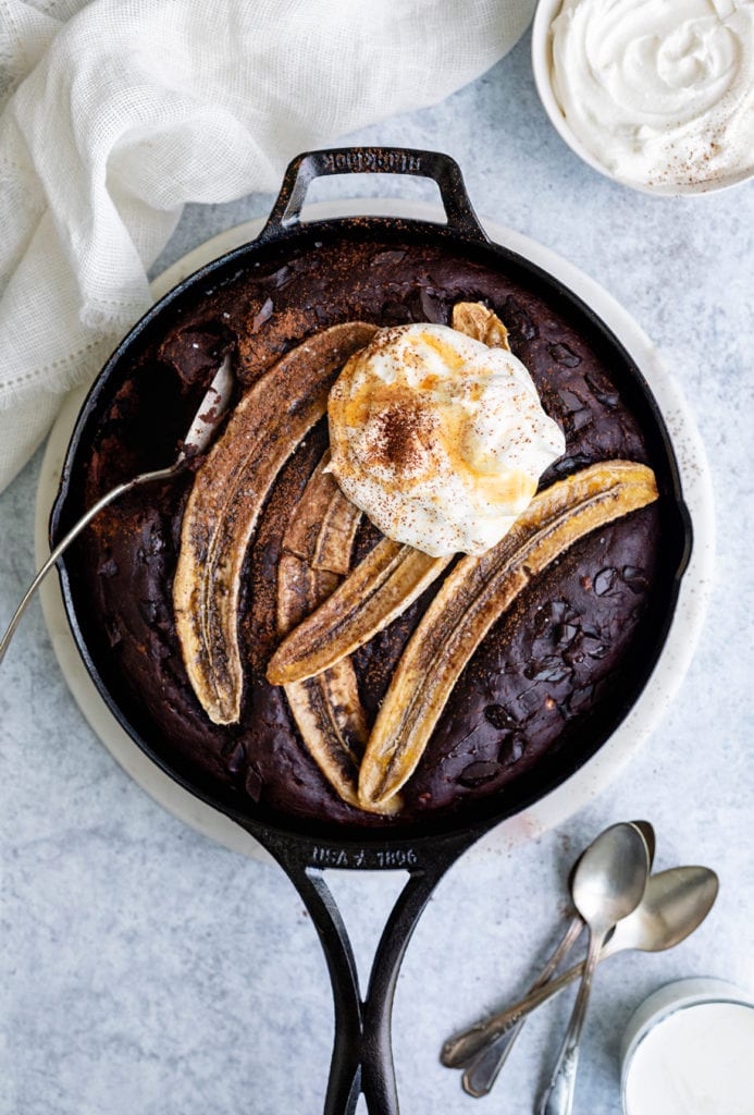 overhead degree angle of chocolate skillet banana bread with spoons and whipped yogurt