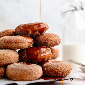Cozy baked apple cider donuts are the perfect fall treat. Covered in browned butter and cinnamon sugar and topped with warm maple.