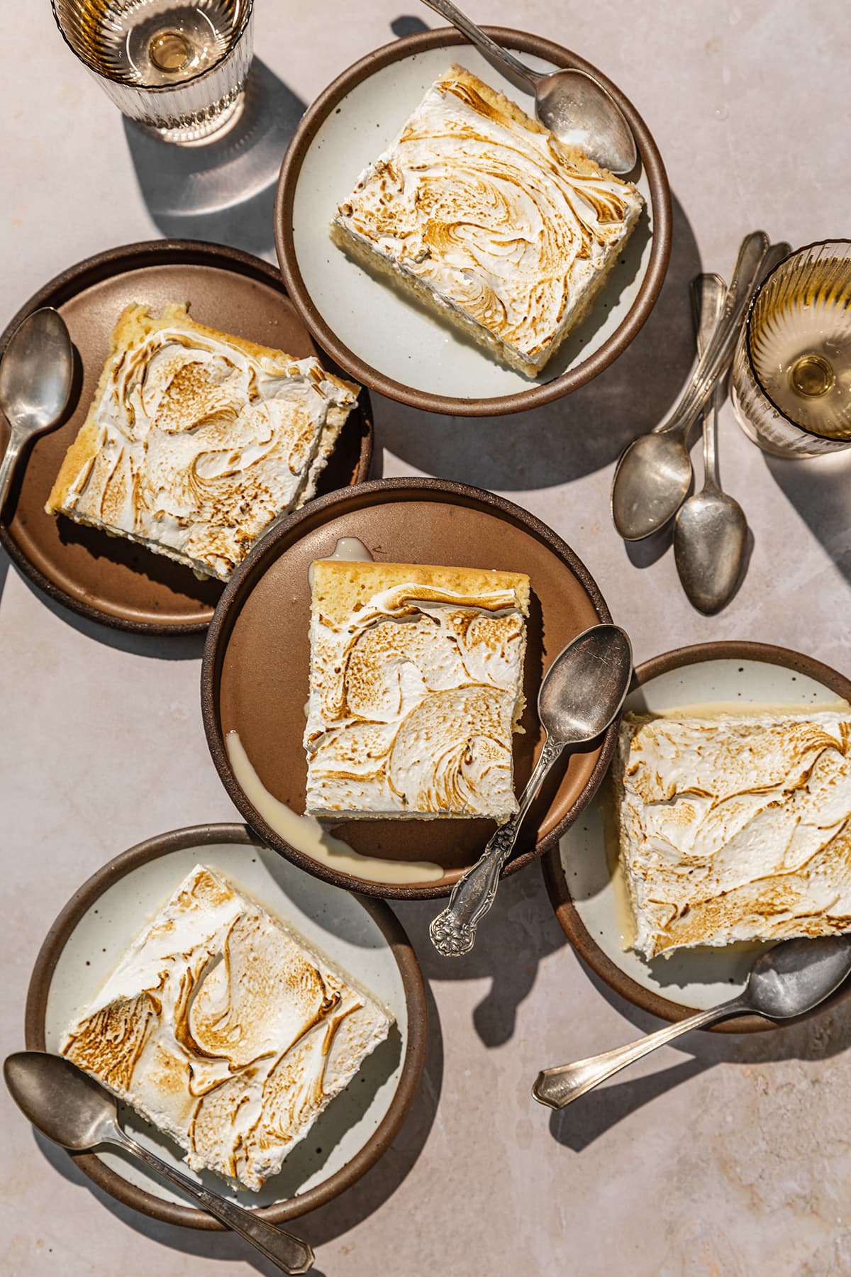 tres leches cake slices with meringue topping served on dessert plates with spoons