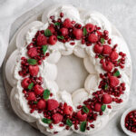 A delicate and crunchy meringue shell with a marshmallow-like center Christmas Pavlova Wreath topped with almond cream and raspberries.