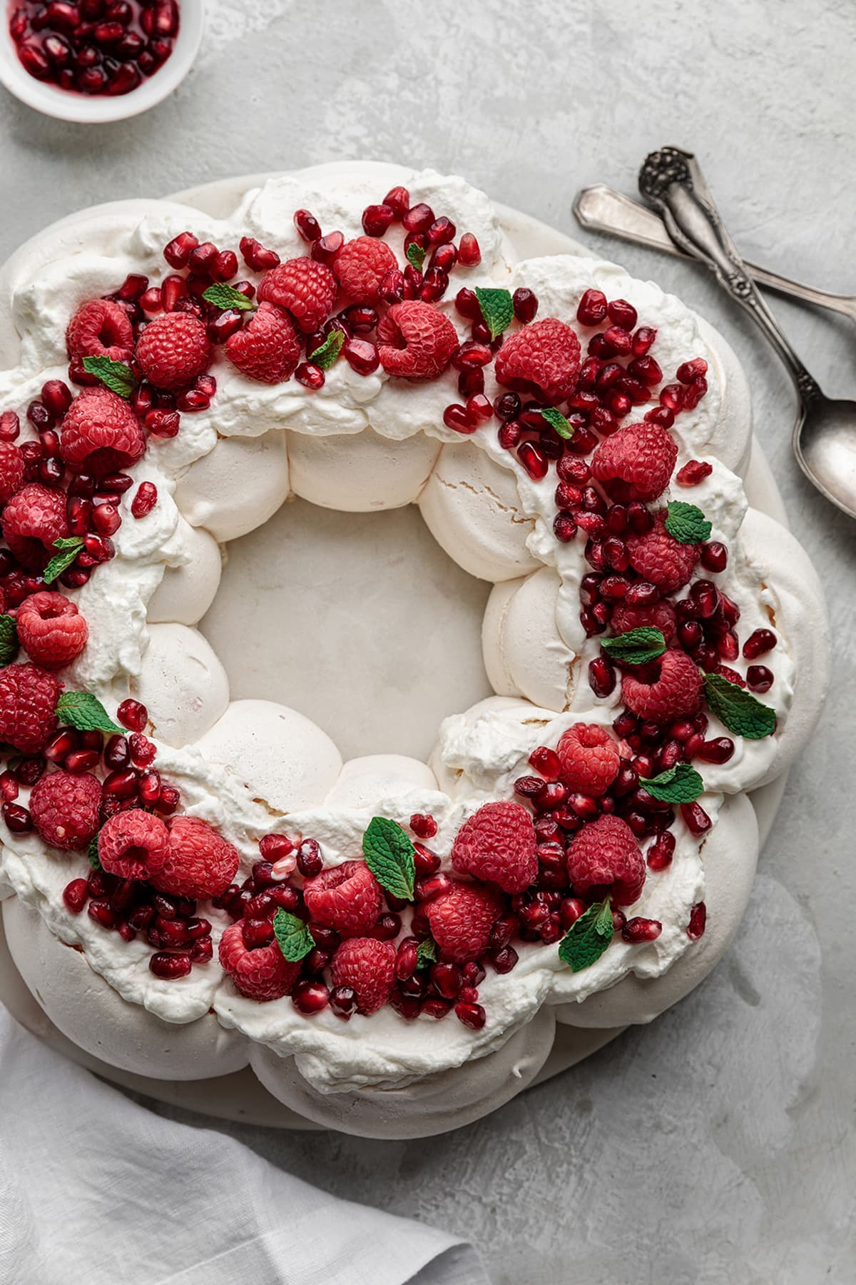 Crunchy meringue shell with a marshmallow-like center Christmas Pavlova Wreath topped with almond cream and raspberries.