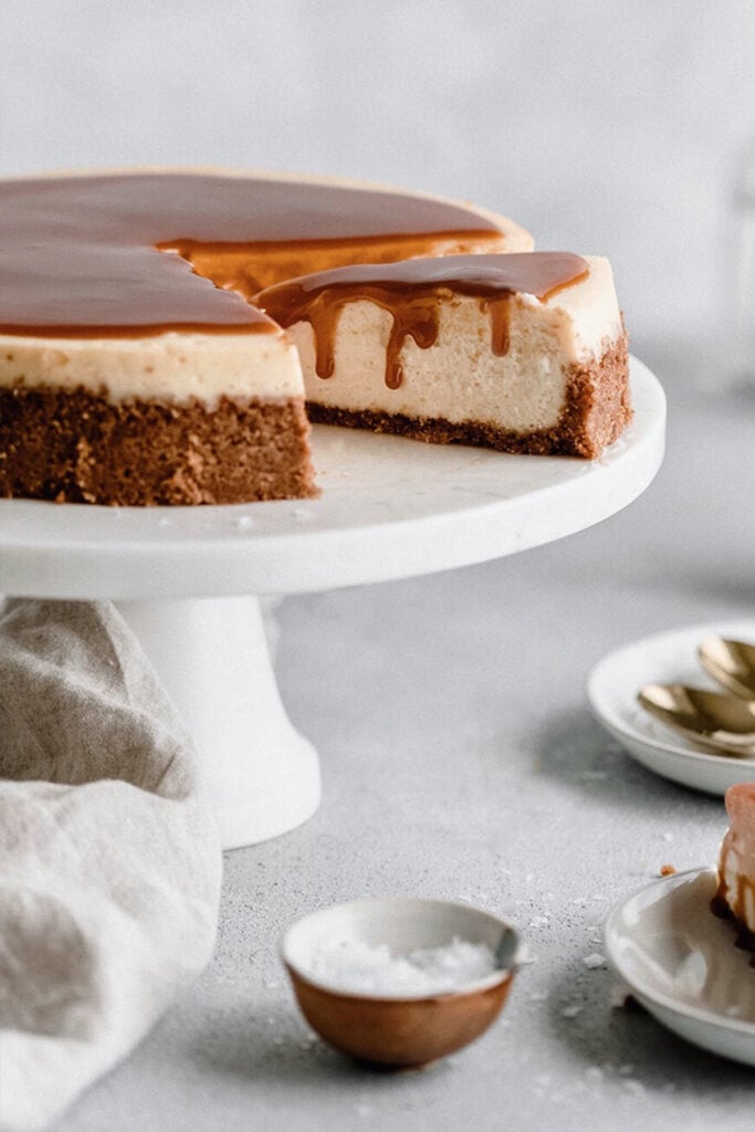 Cheesecake slice served with homemade caramel sauce, on a cake stand