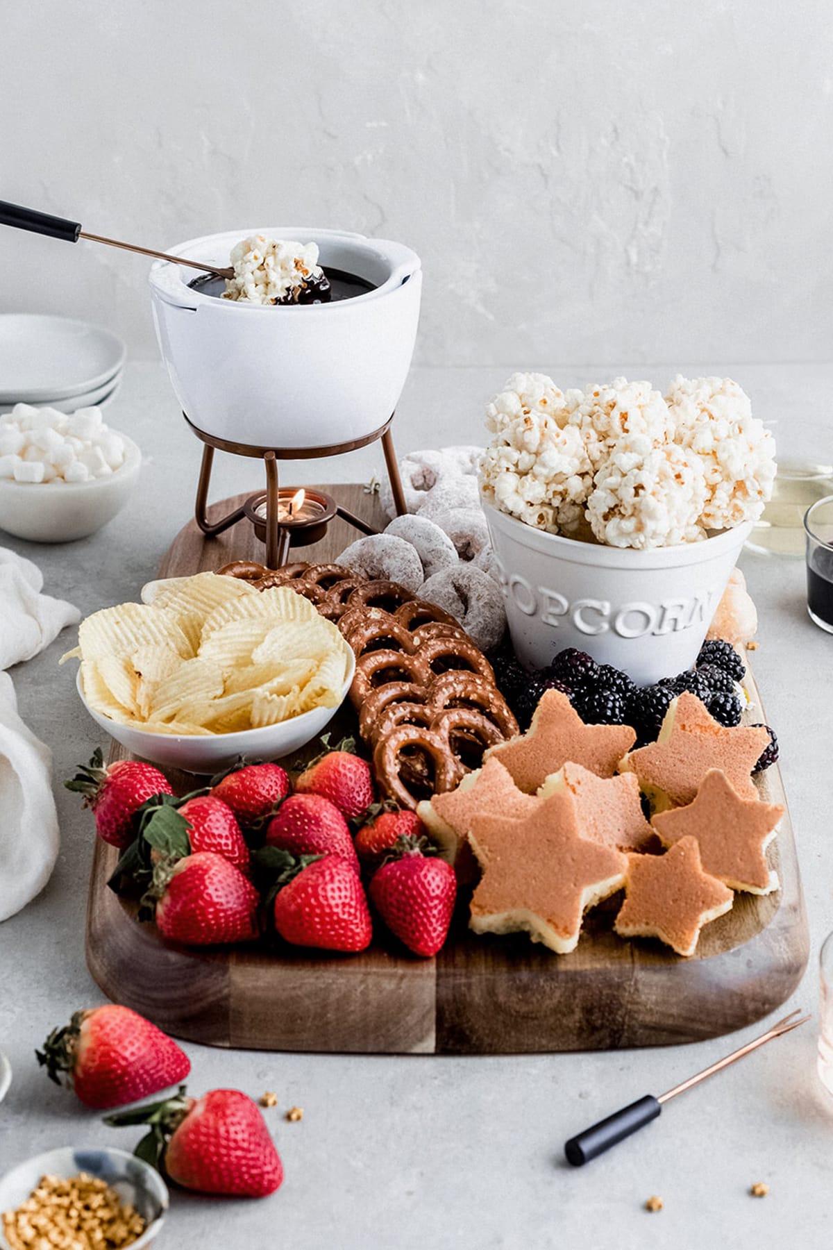 chocolate fondue dessert board with popcorn balls, pound cake, strawberries and pretzels.